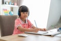 Asian girl student video conference e-learning with teacher on computer in living room at home. Homeschooling and distance Royalty Free Stock Photo