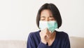 Asian girl symptom cough and are protective with medical mask while sitting on sofa, Asia child wearing a protection mask epidemic Royalty Free Stock Photo