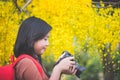 Asian girl take photo with blooming yellow flower Royalty Free Stock Photo