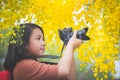 Asian girl take photo with blooming yellow flower Royalty Free Stock Photo