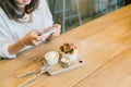 Asian girl taking photo of chocolate toast cake, ice-cream, and milk at coffee shop. Dessert or food photograph hobby Royalty Free Stock Photo