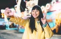 Asian girl taking selfie with mobile phone in amusement park - Happy woman having fun with new trends smartphone apps Royalty Free Stock Photo