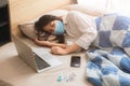 Asian girl teen sick illness lay on bed wearing face mask with laptop computer