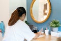 Asian girl teenager with long hair wearing white t-shirt sitting upright doing homework in bedroom When studying at home,