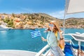 Girl traveler with backpack and hat enjoys a sea cruise on a open ship deck. Tourism and vacation in Greece and Royalty Free Stock Photo