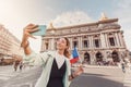 Asian girl traveler with phone near the main Facade of the Opera Garnier in the historic building of the Academy of music of Royalty Free Stock Photo