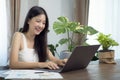 Asian girl typing data to her computer notebook for prepare her report on the wooden deak Royalty Free Stock Photo