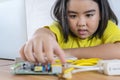 Asian girl using a laptop while assembling a robot from plastic bricks. Royalty Free Stock Photo