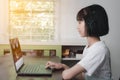 An Asian girl is using a laptop computer to study online.