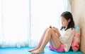 Asian girl using smartphone near window in bedroom at home,technology and communication concept