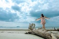 Asian girl walking on death tree on sandy beach