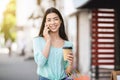 Asian Girl Walking Outdoors With Coffee And Shopping Bags, Talking On Cellphone Royalty Free Stock Photo