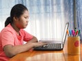 An Asian girl is watching a computer screen to learn online on a notebook. Learning from home concepts.