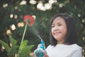 Asian girl watering a red flower in the garden Royalty Free Stock Photo