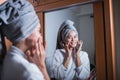 Asian girl wearing bathrobe and hair towel smiling with fingers touching cheeks