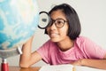 Asian girl wearing glasses is smiling and using a magnifying glass in the classroom, Educational concept Royalty Free Stock Photo