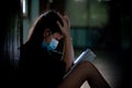 Asian girl wearing a mask sits and reads a book with stress and doesn`t understand. Concept of learning problems during state