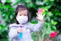 Asian girl wearing white medical face mask. Raise your hand as sign to stop others from getting close.