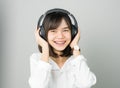 Asian girl in white casual dress listening to music from black headphones. Royalty Free Stock Photo