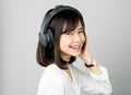 Asian girl in white casual dress listening to music from black headphones. Royalty Free Stock Photo