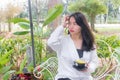 An Asian girl in white coat sitting and holding a black cup of coffee in her hand on the white bench under the morning light. Royalty Free Stock Photo