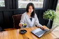 An Asian girl in white shirt plays notebook on wooden table in black room. Royalty Free Stock Photo