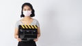 Asian Girl or woman wear face mask and holding black clapper board or movie slate use in video production ,film, cinema industry Royalty Free Stock Photo