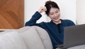 Asian Girl Working on Laptop Online, Using Internet, Sitting on Sofa at Home, Free Space