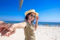 Asian girlfriend wear hat leading man hand to travel on sea beach Royalty Free Stock Photo