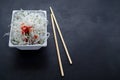 Asian glass rice noodles with vegetables and herbs on white deep square plate on black slate background with copy space. oriental