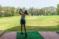 Asian golfer woman swing golf ball practice at golf driving range for relax and healthy care port. Royalty Free Stock Photo