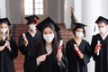 Asian graduate in medical mask pointing