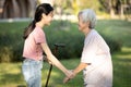 Asian granddaughter is giving a walking stick to her old grandmother,persuade her senior woman to take a walk,exercise in the