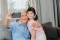 Asian grandfather and granddaughter video call at home. Senior Chinese grandpa happy with young girl using mobile phone video call Royalty Free Stock Photo