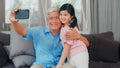 Asian grandfather and granddaughter video call at home. Senior Chinese grandpa happy with young girl using mobile phone video call Royalty Free Stock Photo