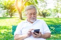 Asian grandfather texting to family by using mobile phone, internet online at park. Old man doing on application of net banking by Royalty Free Stock Photo