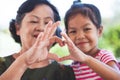 Asian grandmother and little child girl making heart shape with hands together