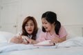 Asian grandmother looking granddaughter drawing at home. Senior Chinese, grandma happy relax with young girl before bedtime lying