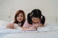 Asian grandmother looking granddaughter drawing at home. Senior Chinese, grandma happy relax with young girl before bedtime lying