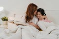 Asian grandmother read fairy tales to granddaughter at home. Senior Chinese, grandma happy relax with young girl enjoy good