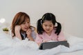 Asian grandmother using tablet read fairy tales to granddaughter at home. Senior Chinese, grandma happy relax with young girl