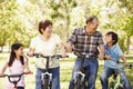 Asian grandparents and grandchildren riding bikes in park Royalty Free Stock Photo