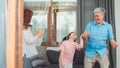 Asian grandparents and granddaughter listen to music and dance together at home. Senior Chinese, grandpa and grandma happy spend