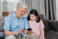 Asian grandparents and granddaughter using mobile phone at home. Senior Chinese, grandpa and kid happy spend family time relax Royalty Free Stock Photo