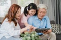 Asian grandparents and granddaughter using tablet at home. Senior Chinese, grandpa and grandma happy spend family time relax with