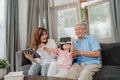 Asian grandparents and granddaughter using virtual reality and tablet play games at home. Senior Chinese, grandpa and grandma