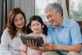 Asian grandparents and granddaughter video call at home. Senior Chinese, grandpa and grandma happy with girl using mobile phone Royalty Free Stock Photo