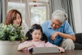 Asian grandparents and granddaughter video call at home. Senior Chinese, grandpa and grandma happy with girl using mobile phone Royalty Free Stock Photo