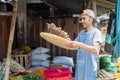 Asian grocer holding a woven bamboo tray sifting turmeric to clean Royalty Free Stock Photo