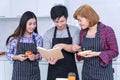 Groups of friends cooking together meal food in the kitchen. Cheerful smiling young man holding book learning cook with his